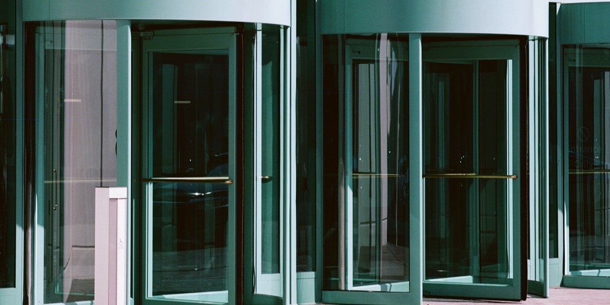 A set of metal revolving doors, with full-height glass panes